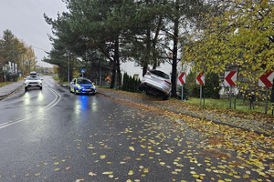 Na zdjęciu widać uszkodzony srebrny samochód, miejsce zdarzenia drogowego, radiowóz.