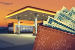 Na grafice widać stację paliw w tle i portfel z pieniędzmi na pierwszym planie.