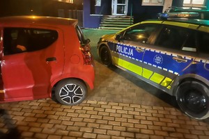 Na zdjęciu widać radiowóz oraz czerwony samochód.