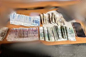 Na zdjęciu widać banknoty i inne przedmioty rozłożone na stole.