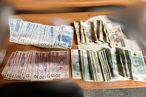 Na zdjęciu widać banknoty i inne przedmioty rozłożone na stole.