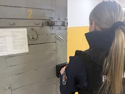 Na zdjęciu widać policjantkę, która zamyka drzwi celi.