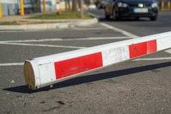 Grafika przedstawia uszkodzony szlaban leżący na jezdni, obok jezdnię i nadjeżdżający pojazd.