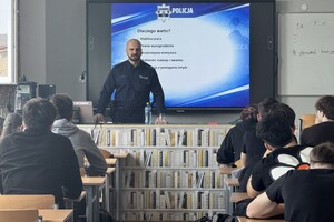 Na zdjęciu widać policjanta i uczniów zgromadzonych w sali.