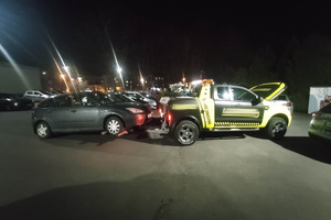 Na zdjęciu widać ciemny holowany samochód, a także autolawetę.