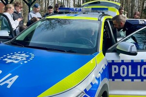 Na zdjęciu widać policjantów i uczniów w trakcie wspólnych zajęć profilaktycznych w terenie.