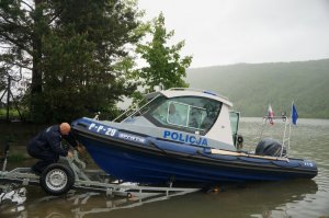 policjant odczepia łódkę z wózka samochodowego