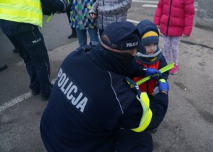 policjant wręcza odblask dziecku