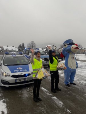 ouczestnicy akcji stoją na tle radiowozów i machają dzieciom