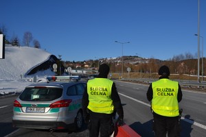 funkcjonariusz esłużby celnej stoją obok siebbie obok zaparkowany samochód straży granicznej w tle droga