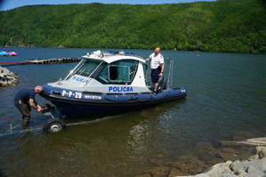 wodowanie łódki łódka podczas zjeżdżania z wózka na łódce stoi policjant obok pasy odpina pracownik