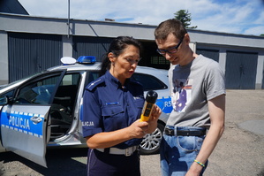 policjantka tłumaczy chłopcu w jaki sposób bada się stan trzeźwości w tle radiowóz