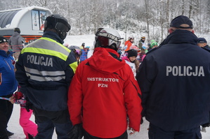 tyłem stoją policjanci i instruktorzy PZN w tle stok z narciarzami