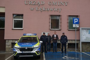radiowóz zaparkowany przed budynkiem urzędu gminy w Gilowicach obok stoją policjanci oraz wójt