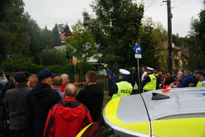 fragment radiowozu w tle policjanci oraz mieszkańcy obserwujący rajd