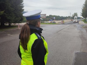 policjantka stoi tyłem w tle trasa rajdu i samochód