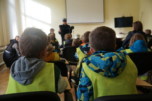 zbliżenie na dwoje dzieci siedzących tyłem policjantka w tle