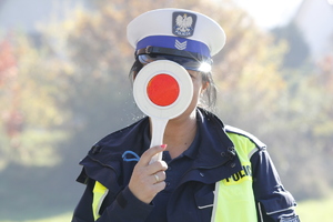 zdjęcie kolorowe policjantka trzyma na wysokości twarzy tarczę do zatrzymywania pojazdów
