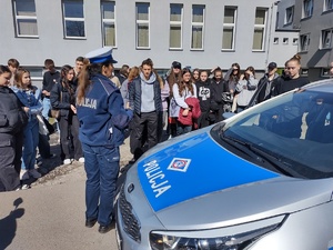 zdjęcie kolorowe zrobione na zewnątrz policjantka prezentuje radiowóz