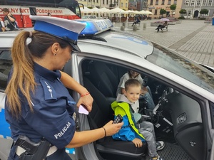 policjantka stoi przy radiowozie w którym siedzą dzieci