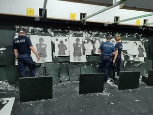 zdjęcie kolorowe policjanci wspólnie z instruktorem oceniają wyniki strzelania