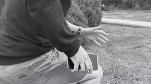 czarno białe zdjęcie fragmentu osoby i dłoni która trzyma telefon