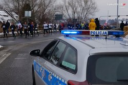 zdjęcie kolorowe stojący radiowóz w tle biegacze
