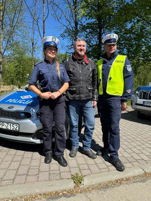 policjanci stoją obok siebie z motocyklistą