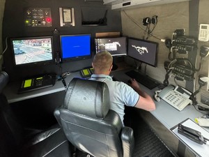 policjant siedzi tyłem przed monitorami