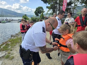 policjant zapina dziewczynce kamizelkę ratunkową