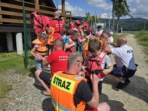 dzieci zakładają kamizelki ratunkowe