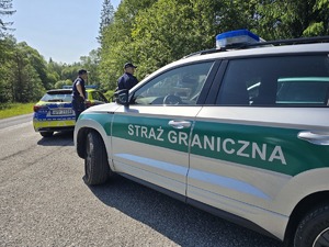 samochód ze straży granicznej w tle radiowozy i policjanci