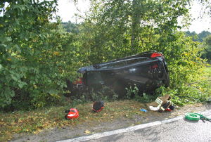 zdjęcie kolorowe, samochód na boku leży w krzakach