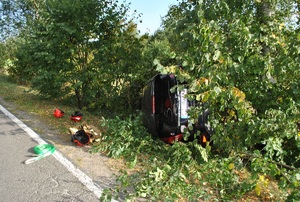 zdjęcie kolorowe, samochód na boku leży w krzakach