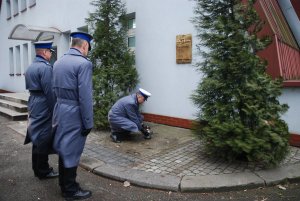 Delagacja zapala znicz przed tablicą pamiątkową usytuowaną na murze hali sportowej Oddziału Prewencji Policji w Katowicach