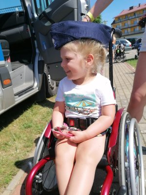 5-letnia podopieczna fundacji SMA z założoną furażerką policyjną na wózku inwalidzkim.