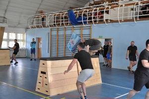 Zawodnicy skaczą przez skrzynię podczas biegu wahadłowego.