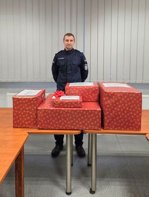 Główny organizator akcji w OPP w Katowicach sierż.szt. Mateusz Ceremuga z zapakowanymi paczkami.