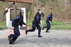 3-osobowa drużyna policjantów biegnie na linię strzału.