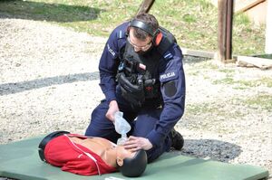 Policjant wykonuje sztuczne oddychanie za pomocą worka samorozprężalnego na fantomie do pierwszej pomocy.