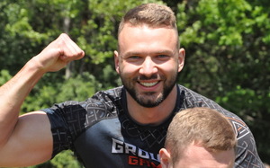 Bliskie ujęcie zawodnika z szerokim uśmiechem prężącego biceps.