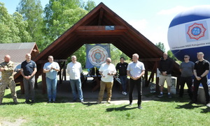 Zastępca Dowódcy OPP w Katowicach przemawia na zakończenie zawodów. Obok główny sędzia i inne osoby zaangażowane w organizację oraz przedstawiciele podmiotów wspierających.