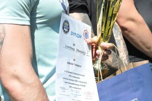 Zbliżenie na trzymane przez zawodnika puchar i dyplom dla drużyny, która zajęła 3 miejsce w zawodach.