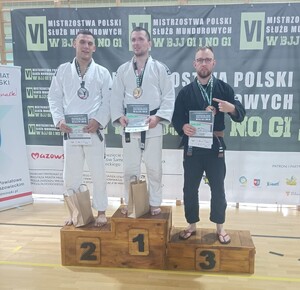Sierżant Maciej Tworzydło ze złotym medalem i dyplomem na najwyższym stopniu podium. Na miejscach drugim i trzecim pozostali zawodnicy.